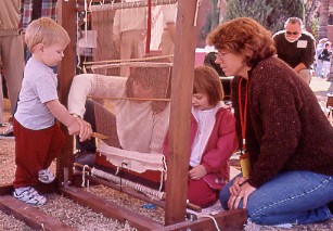 Volunteers helping children learn to weave